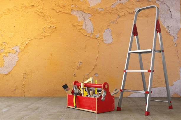 Home renovation and improvement concept. Ladder, toolbox with tools and old grunge wall in the room.