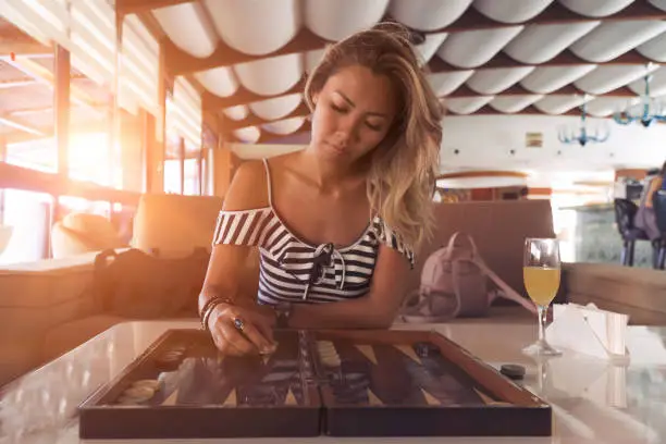 Young woman playing backgammon in hotel lobby