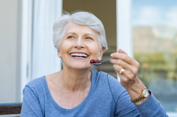 старшая женщина ест фрукты - aging process morning outdoors horizontal стоковые фото и изображения