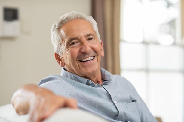 älterer mann lächelnd zu hause fühlen - ältere männer stock-fotos und bilder