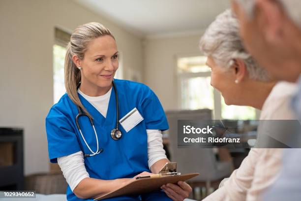 Friendly Nurse Talking With Old Couple Stock Photo - Download Image Now - Nurse, Patient, Doctor