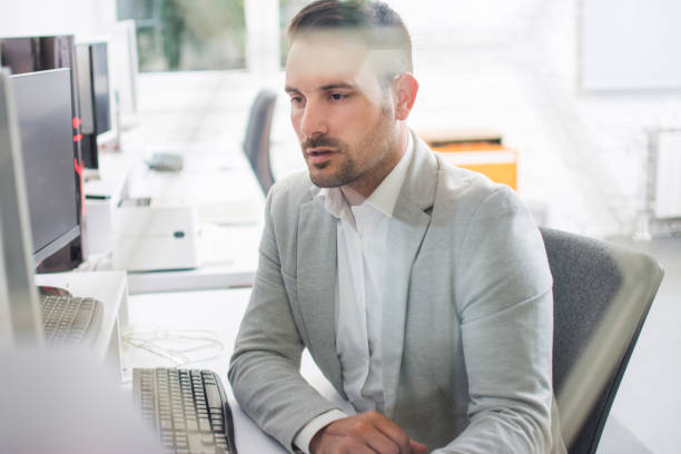 istock Through glass view of concentrated business man working on computer at office 1029342978