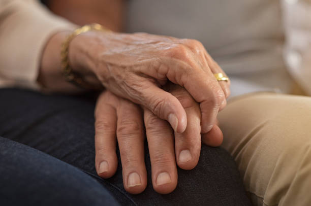 Senior couple holding hands Closeup of elderly couple holding hands while sitting on couch. Husband and wife holding hands and comforting each other. Love and care concept. old hands stock pictures, royalty-free photos & images