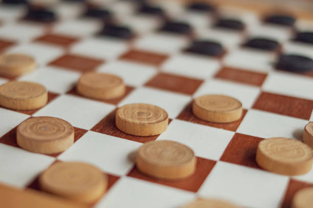 istock Playing checkers with wooden black and white pawns 1029343556