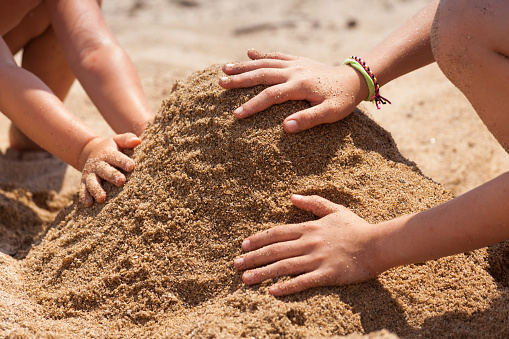 Two children building sand castle together.