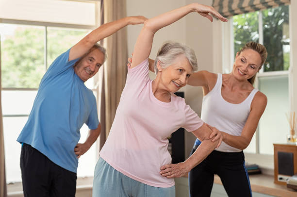 physiotherapeuten helfen älteres paar übung - senior adult sport yoga exercising stock-fotos und bilder