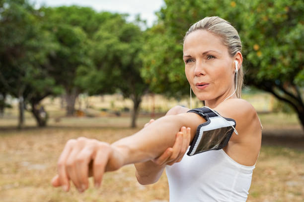 dojrzała kobieta rozciągająca się w parku - breathing exercise jogging exercising relaxation exercise zdjęcia i obrazy z banku zdjęć