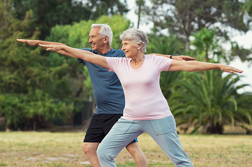 Senior couple doing sport and physical exercises outdoor. Active senior man and elderly woman doing workout at park. Aged couple doing their stretches in the park.