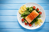Grilled salmon with French fries and vegetables on wooden table