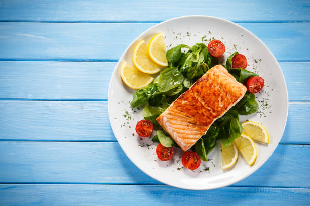 Grilled salmon with French fries and vegetables on wooden table Grilled salmon with French fries and vegetables on wooden table grilled salmon stock pictures, royalty-free photos & images