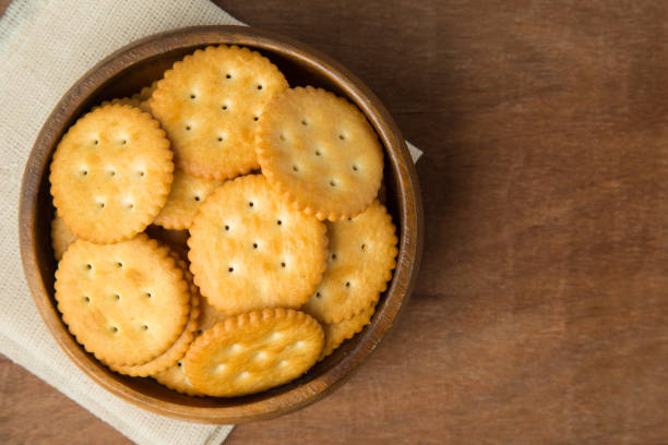 Round salted cracker cookies in wooden bowl putting on linen and wooden background Round salted cracker cookies in wooden bowl putting on linen and wooden background. ritz crackers stock pictures, royalty-free photos & images