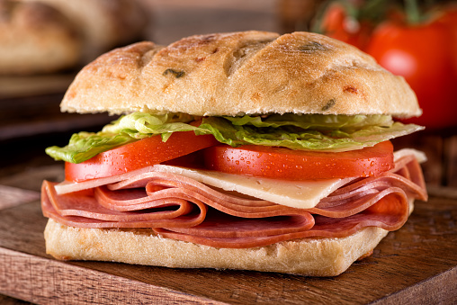 A delicious deli sandwich on cheddar jalapeno ciabatta bread with lettuce and tomato.