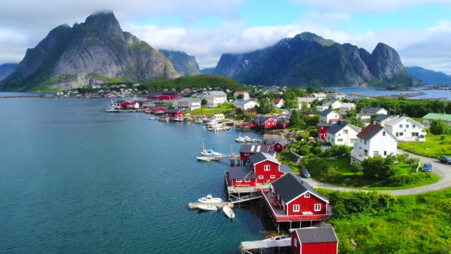Aerial footage of small fishing village of Hamnoy on Lofoten islands in Norway, popular tourist destination with its typical red houses and natural beauty. Aerial 4k Ultra HD.