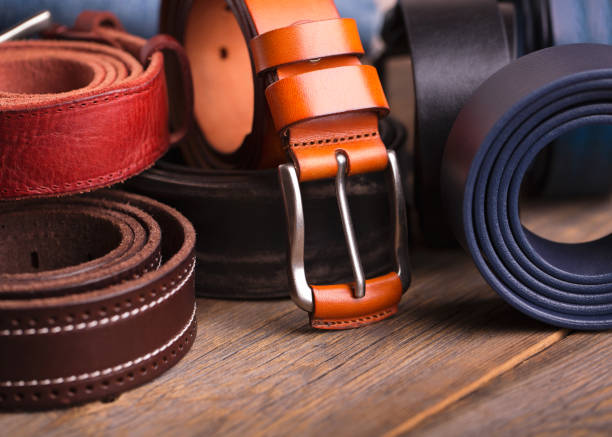 colección de cinturones de cuero sobre una mesa de madera - cinturón fotos fotografías e imágenes de stock