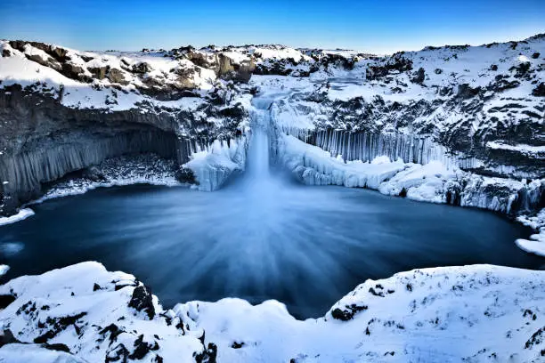 Taken end of January,at -16°c The water fall Aldeyjufoss cascades through a frozen cap into a basalt basin beneath .