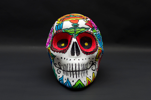 Styrofoam skull hand painted, decorated with mexican flowers against black background