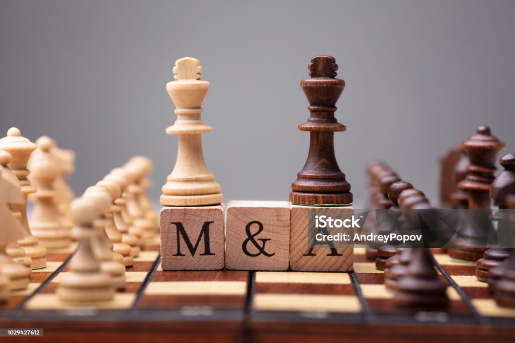 King Chess Pieces With Mergers And Acquisitions Text Close-up Of King Chess Pieces On Wooden Blocks With Mergers And Acquisitions Mergers and Acquisitions Stock Photo