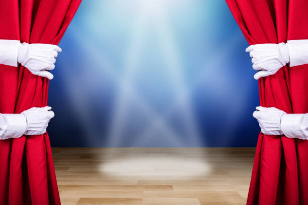Two People Opening Red Stage Curtain With Three Spot Lights In Background