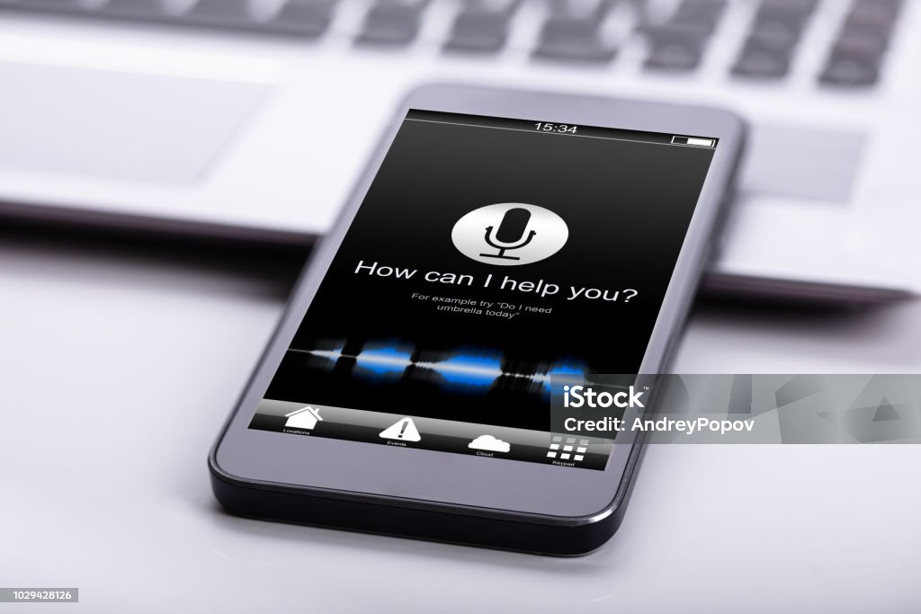 Smart Phone On Desk Smart Phone On Desk With Screen Showing How Can I Help You? Text Voice Stock Photo