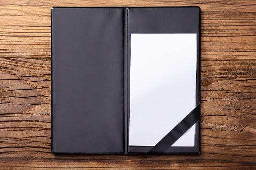 Overhead View Of Blank Empty White Paper In Black Leather Folder On Wooden Table