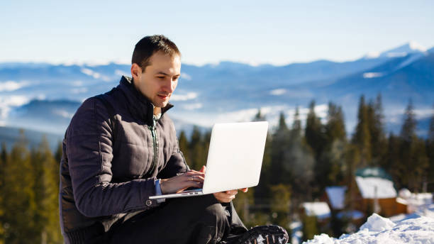istock Side view of a male mountain climber using laptop on mountain peak 1029441464