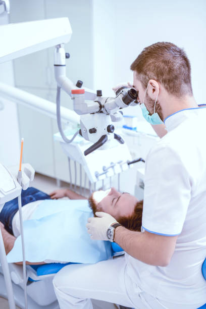 istock Male Dentist Using Microscope To Inspect Patient's Mouth Cavity 1029446764