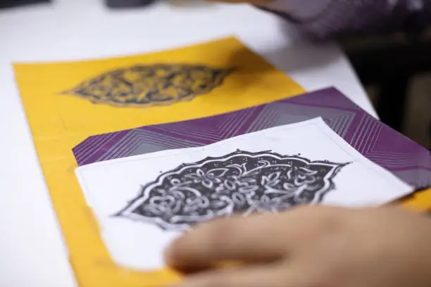 Book binder hand illustrating book covers in his workshop calligraphic patterns at his work table in a close up view