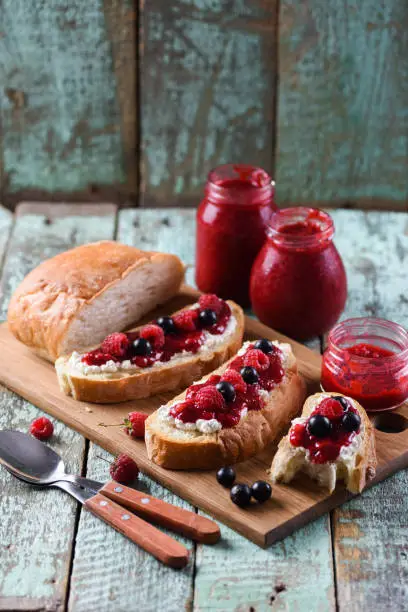 Tasty summer breakfast. Homemade berry jam on ciabatta toasts on old shabby blue boards copyspace
