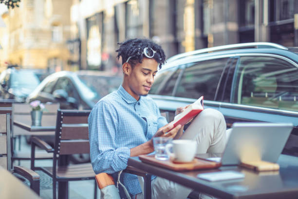 istock Young student is flipping up a book in a sidewalk caffee 1029464276