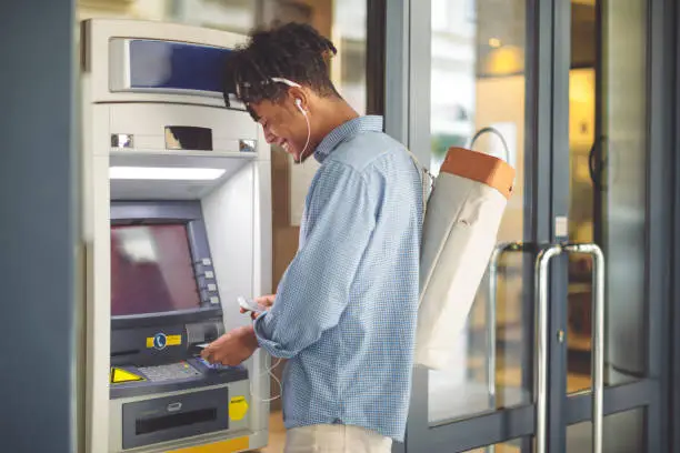 Photo of Young man is withdrawing money from an ATM