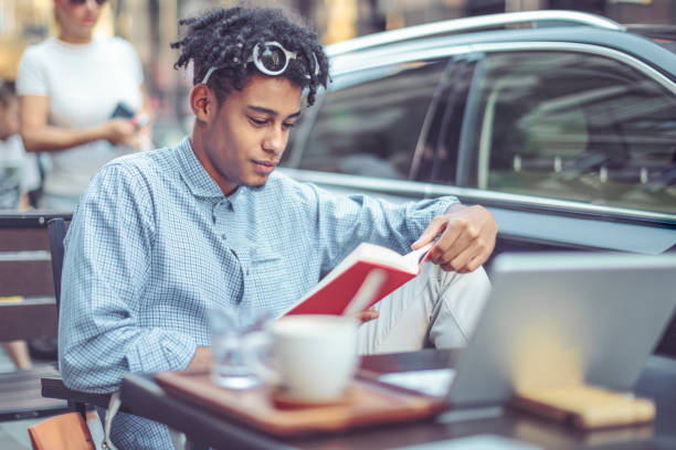 istock Young student is flipping up a book in a sidewalk caffee 1029466666