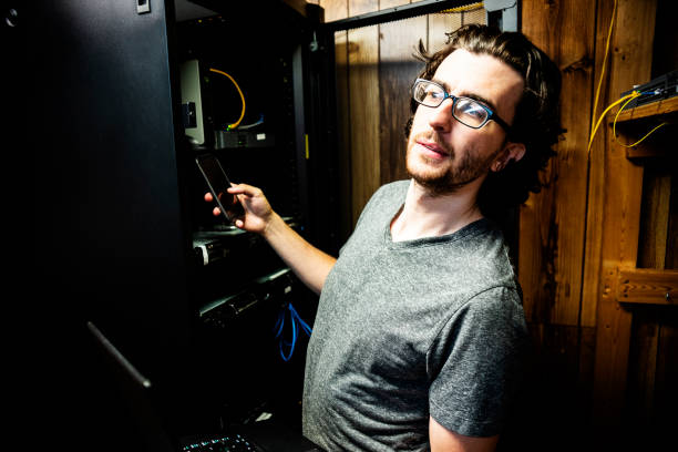 a man stealing data in a small business server room. - employee theft imagens e fotografias de stock