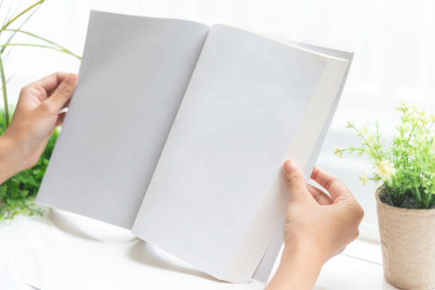 istock Close up of hands holding blank book beside window. 1029491932