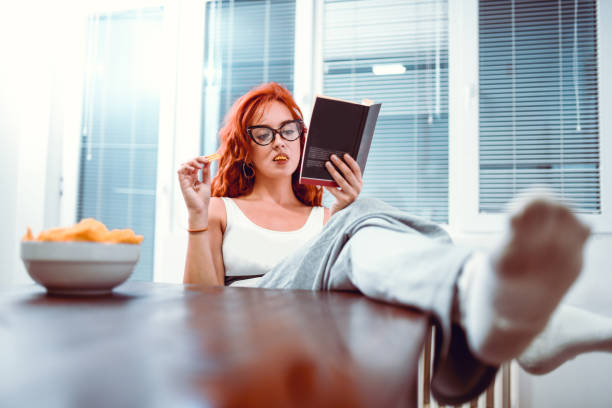 Cute Teen Eating Chips And Reading A Book