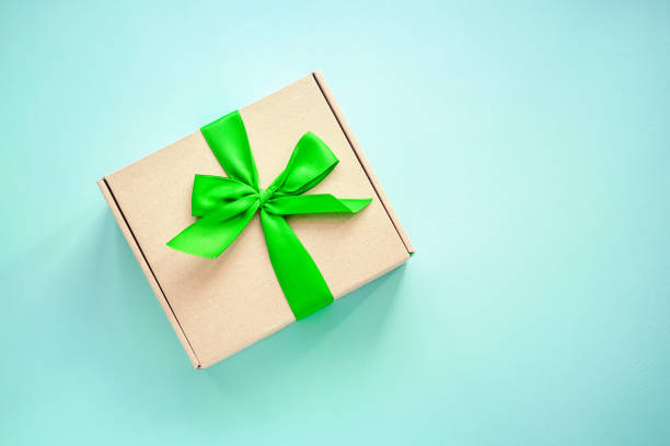 istock Craft paper box with green ribbon bow on blue 1029500736
