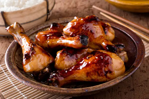 A bowl of delicious honey garlic chicken drumsticks with rice.