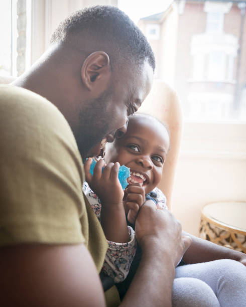 istock Young girl on father's lap looking up and smiling 1029554676