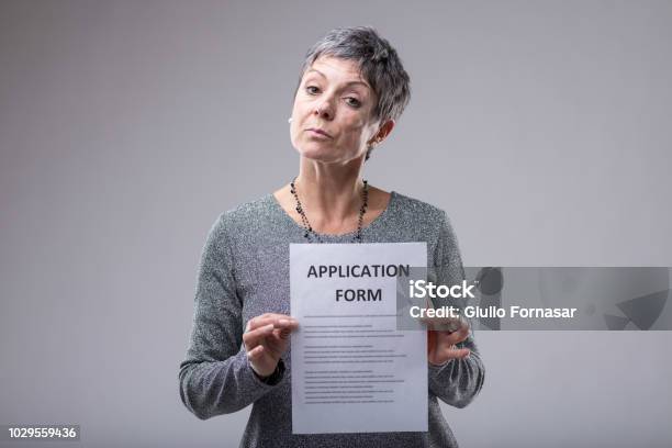 Expectant Woman Holding Up An Application Form Stock Photo - Download Image Now - Application Form, Old, Senior Adult