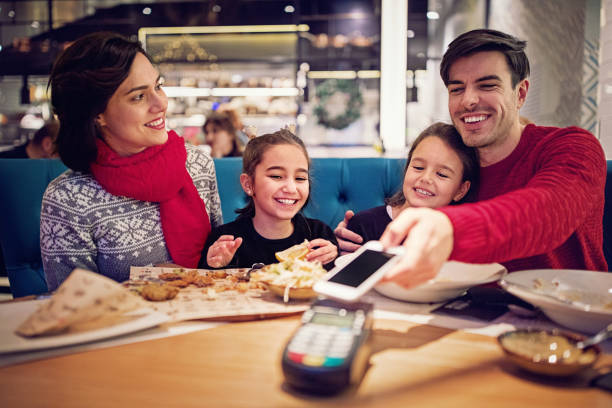 istock Husband is paying using mobile phone in the restaurant at Christmas 1029566282