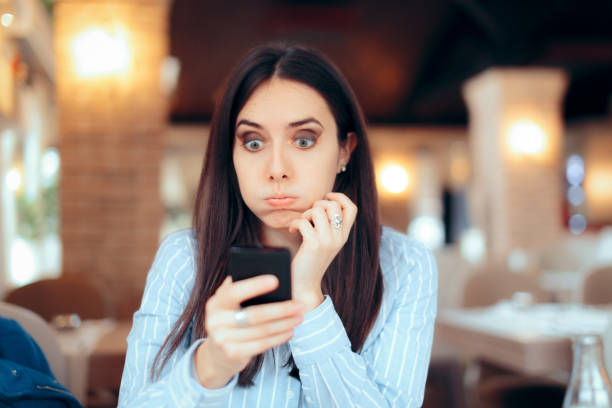 Worried Girl Reading Urgent SMS Text on Smartphone Stressed young woman checking her phone in a restaurant relationship breakup photos stock pictures, royalty-free photos & images