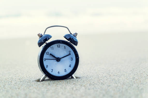 istock vintage alarm clock on sandy beach. selective focus and grain effect 1029645806