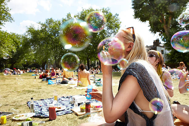 friends blowing bubbles in the park - picknick stock-fotos und bilder