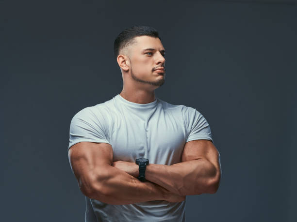 portrait d’un bodybuilder beau musclé en sportswear, debout avec les bras croisés dans un studio. - men muscular build body building sensuality photos et images de collection