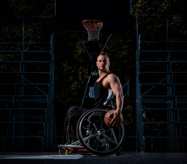 krüppel-basketball-spieler in einem rollstuhl hält einen ball auf ein offener gaming-boden. - men chair wheelchair sport stock-fotos und bilder