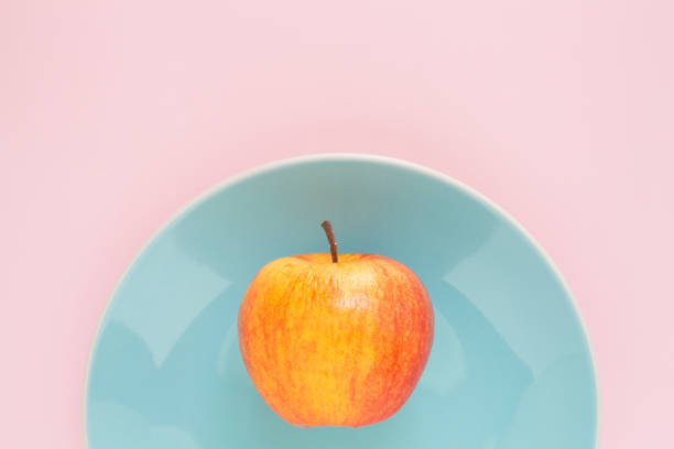 istock red apple on plate blue top focus on pink background 1029704472