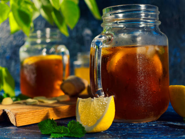 Iced tea with lemon, honey and ginger on the blue table under the tree. Close-up