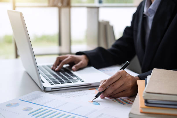 istock Female accountant calculations and analyzing financial graph data with calculator and laptop Business, Financing, Accounting, Doing finance, Economy, Savings Banking Concept 1029711578