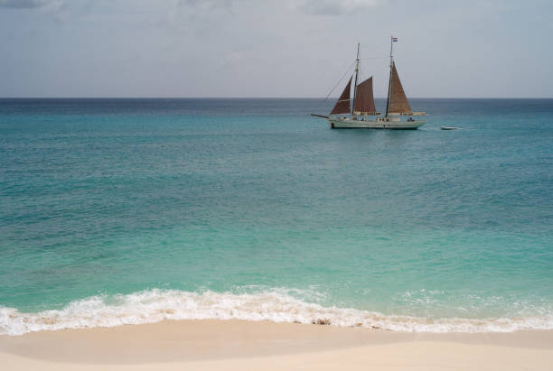 yacht, vorbei an einem schönen strand - cupecoy beach stock-fotos und bilder