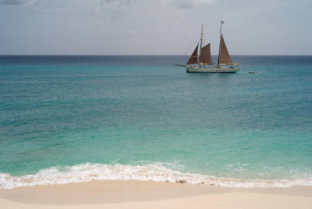 yacht passing a beautiful beach - cupecoy beach imagens e fotografias de stock