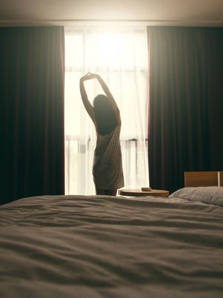 stretching davanti alla finestra della camera da letto - waking up window women morning foto e immagini stock